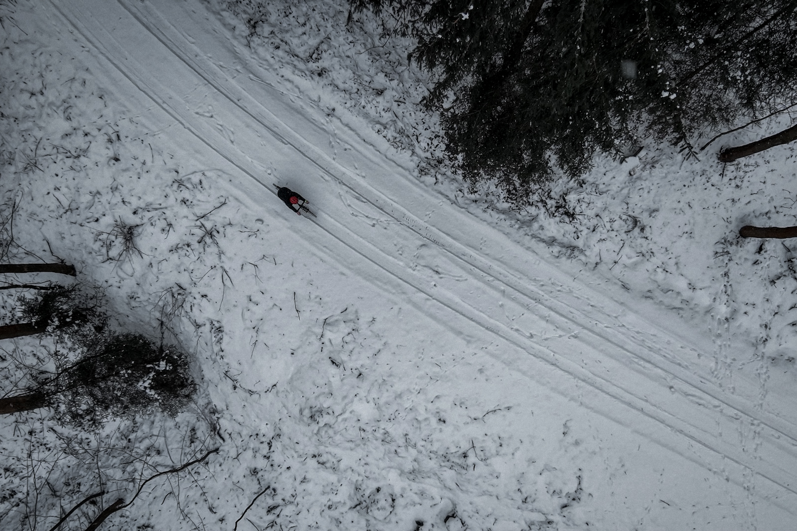 Rowerzysta jadący w zimowych warunkach na drodze widziany z drona