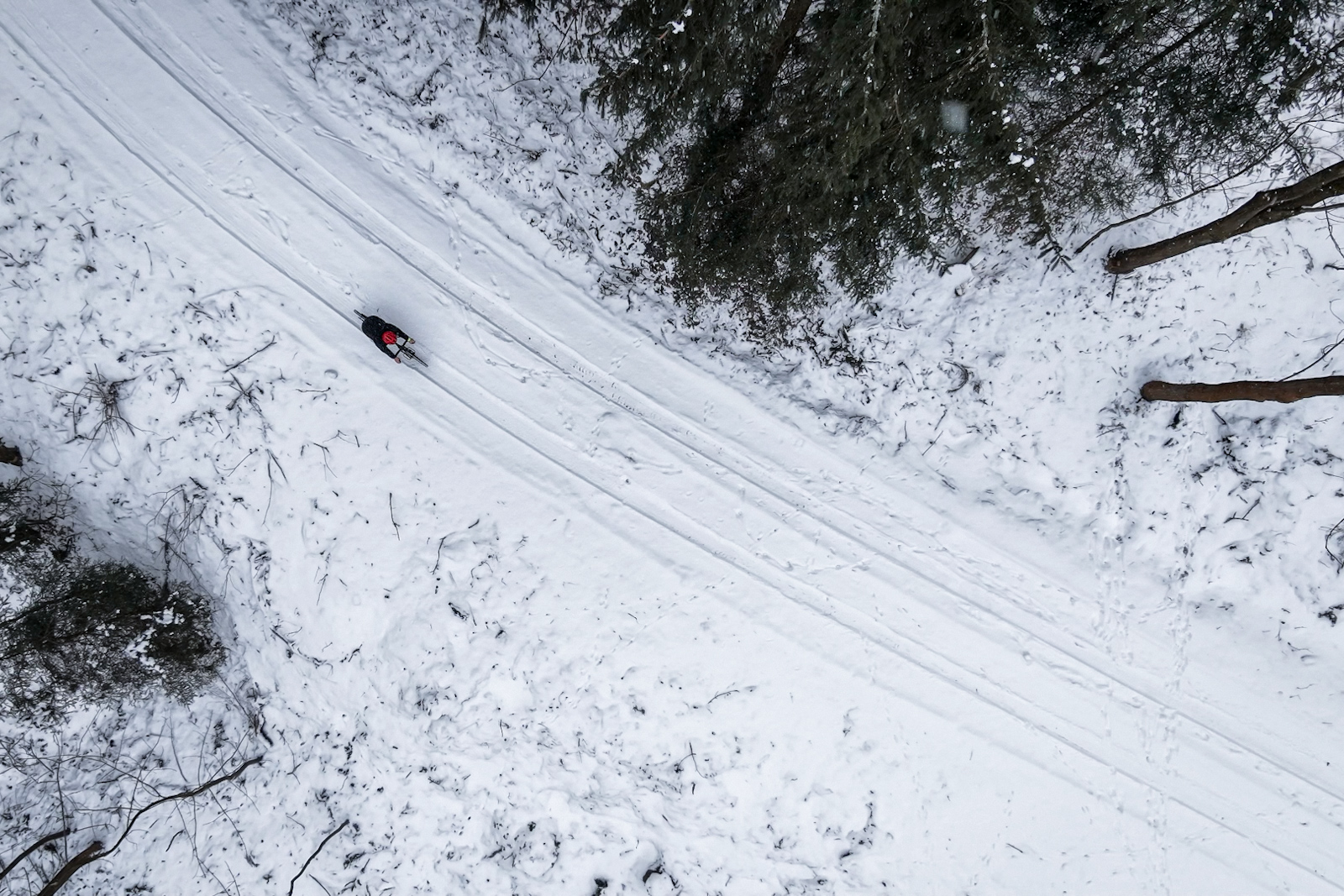 Rowerzysta jadący w zimowych warunkach na drodze widziany z drona