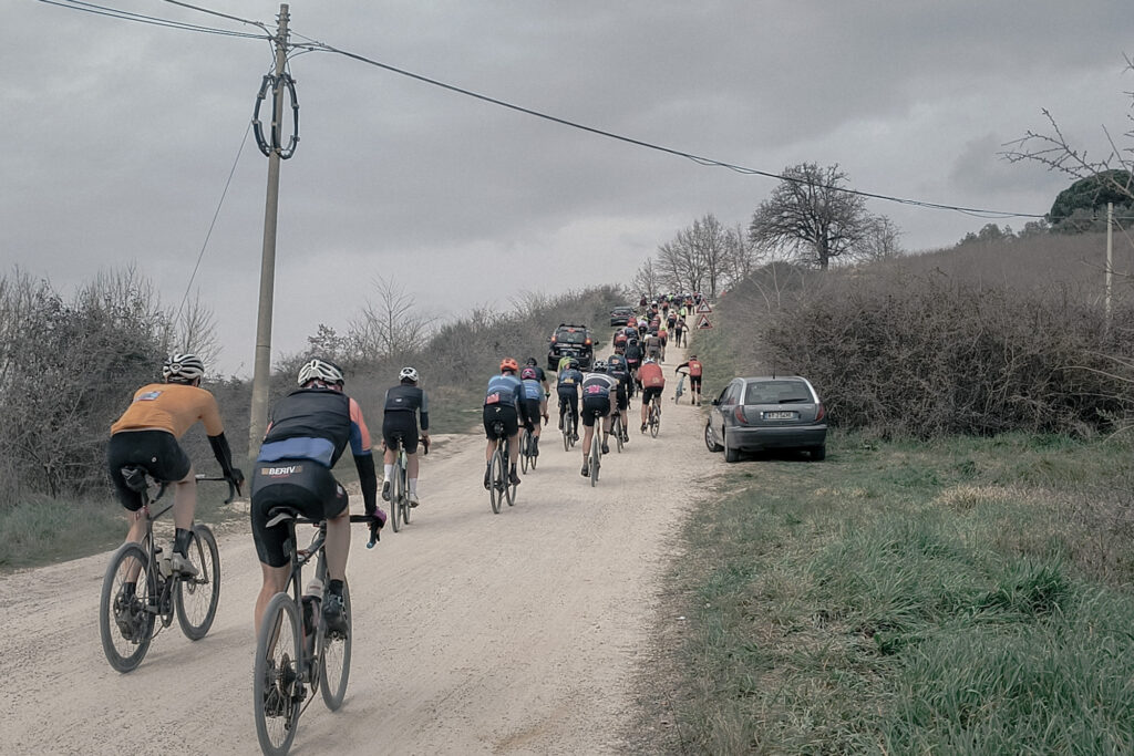 Grupa rowerzystów jadących pod szutrowe wzniesienie podczas zawodów gravelowych
